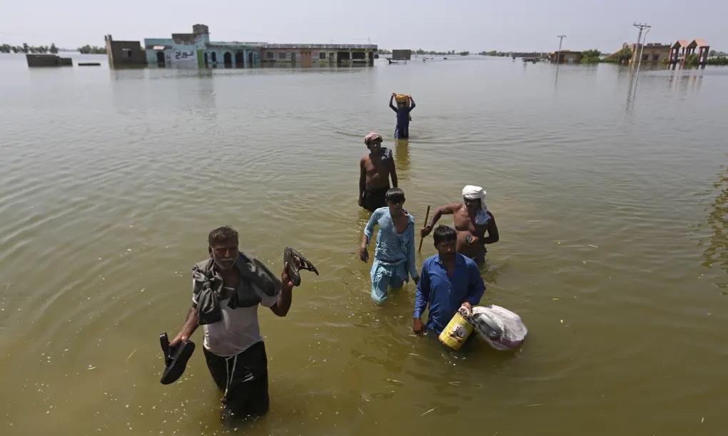 Victims of flooding from monsoon rains carry belongings salvaged from their flooded home in the Dadu district of Sindh province..jpg